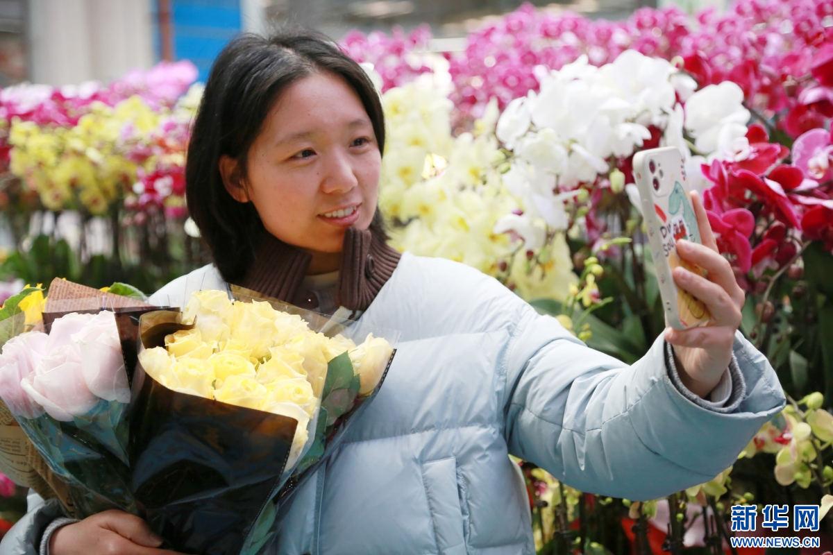 2月8日，游客在云南昆明斗南花卉市场与鲜花合影。新华网发（薛莹莹 摄）