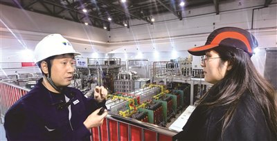 杨园明（左）向记者介绍“玄龙-50U”装置（曹阳 摄）