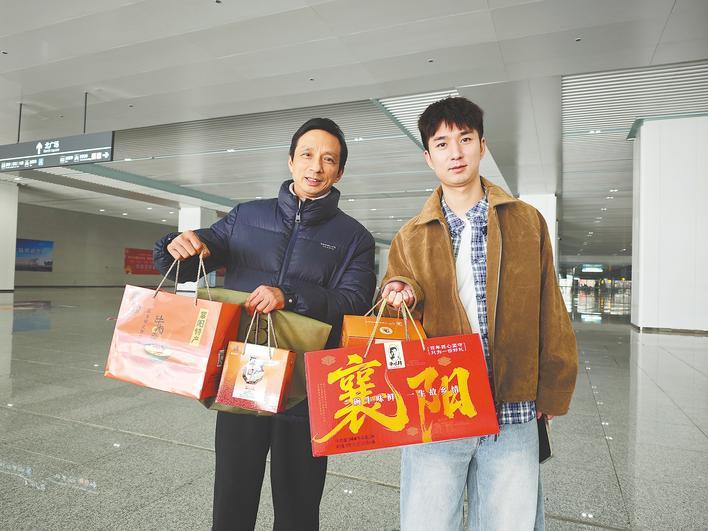 2月20日,来自襄阳的朱俊熙父子俩拎着襄阳特产牛肉面礼盒来宜昌走亲戚。(湖北日报通讯员 邱承娇 摄)