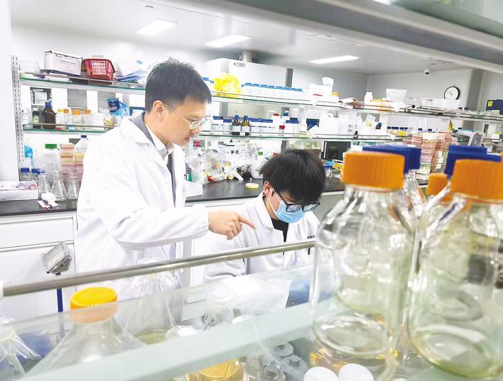 2月11日,湖北江夏实验室,杨航(左)指导团队成员做实验。 (湖北日报全媒记者 文俊 摄)