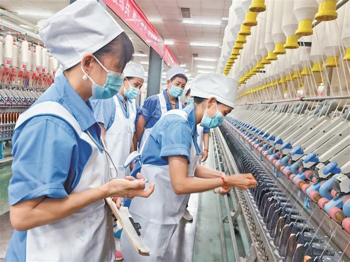 新疆唐成棉业有限公司纺织工人（前）正教新员工熟悉机台操作流程，确保每一道工序精准无误（资料图片）。李俊锋 摄
