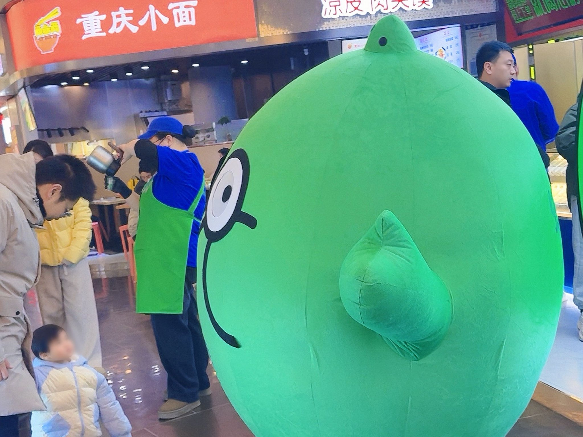 石家庄市欢乐汇怂柠门店前，怂柠人偶与行人互动。于歆/摄