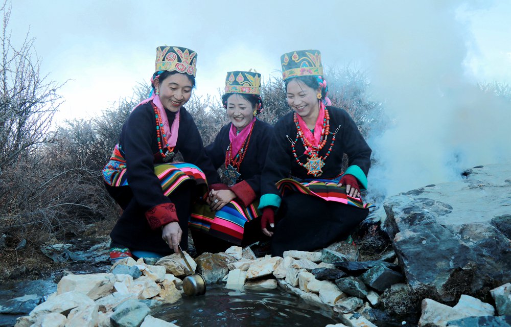 圖為拉東村的婦女們身著盛裝，面帶笑容，用銅勺從溪中取水，祈願新一年五穀豐登。