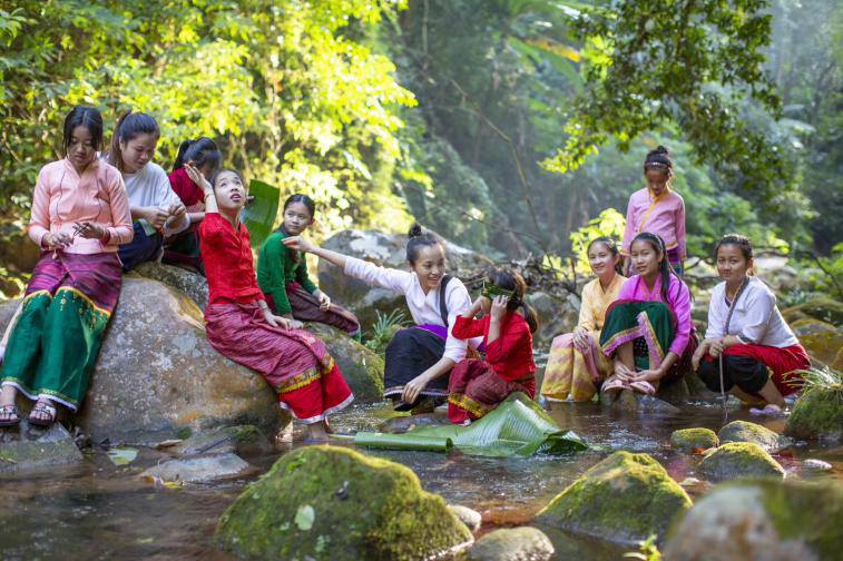 楊磊和孩子們在河邊嬉戲。冉傑文 攝