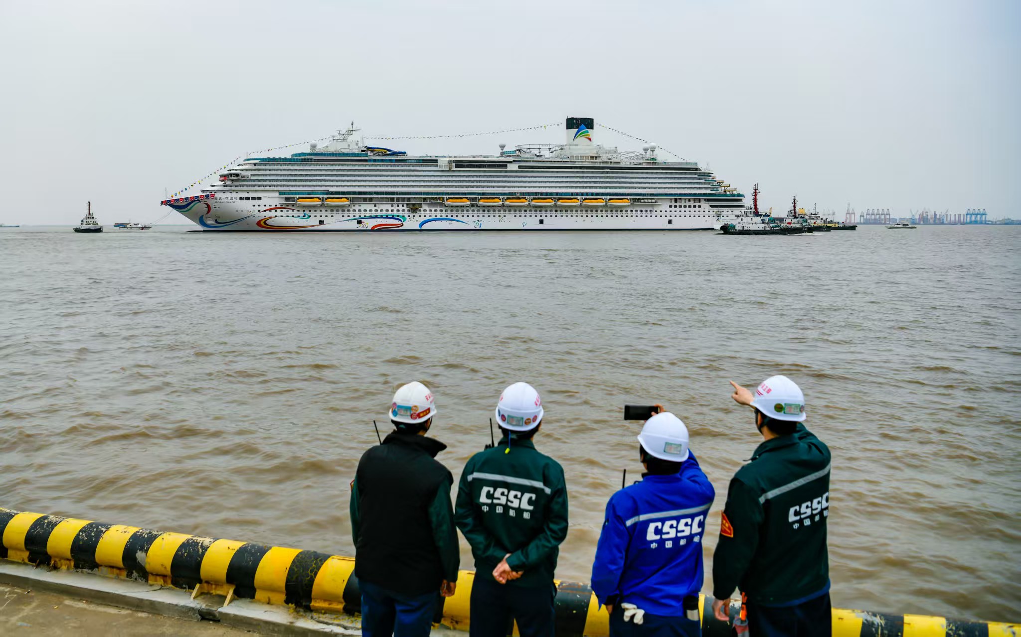 建设者目送“爱达·花城号”被趸船拖至码头。劳动报记者颜筱依 摄影