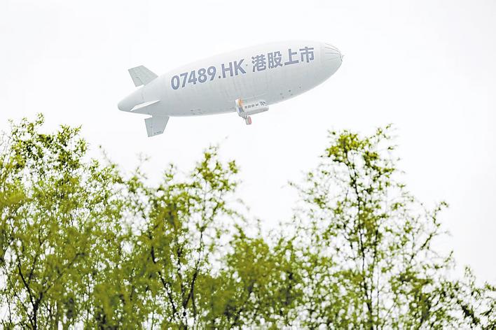 3月19日上午，“岚图汽车”敲钟上市，印有“岚图汽车”股票代码的飞艇飞过武汉上空。 （湖北日报全媒记者 张灿 陈少哲 摄）