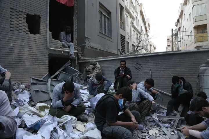 3月15日，在伊朗首都德黑兰的一处遇袭居民区，人们坐在一处建筑废墟上。新华社记者 沙达提 摄