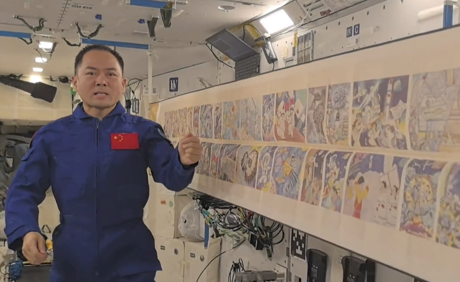 航天員在空間站內展示畫作，講述創作背後的故事。（央視新聞影片截圖）
