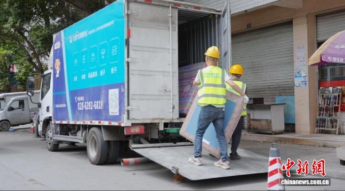 工作人員將舊沙發搬運上車。成都市城管委 供圖
