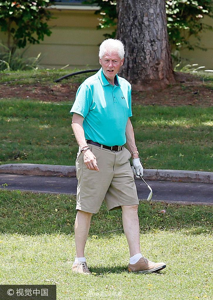 克林顿俯身仔细观察球位，手指轻触草皮评估地形，表情认真如研判国事