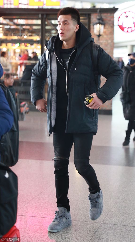 郭艾伦微弓着背，低垂着眼帘，手中握着笔在球迷的卡片上认真划过，身后的机场告示牌虚化成影，疲惫与温柔在这一刻交融