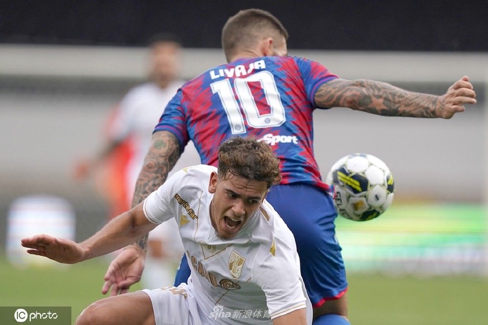 吉马良斯队球员在边路与哈伊杜克防守队员激烈拼抢，双方身体对抗胶着，草皮被鞋钉刮起