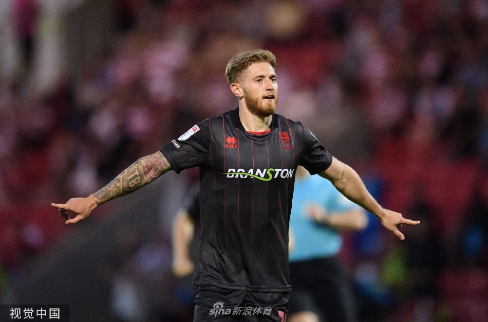 唐卡斯特球员在林肯城严密防守下艰难组织进攻，主队球迷在看台上神情紧张地关注着战局。