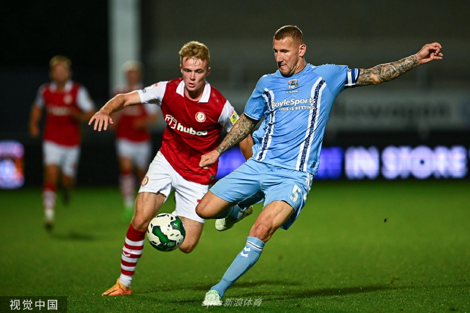 考文垂球员低头走回中圈，神情沮丧，背景中庆祝的布里斯托尔城球员形成了鲜明对比。