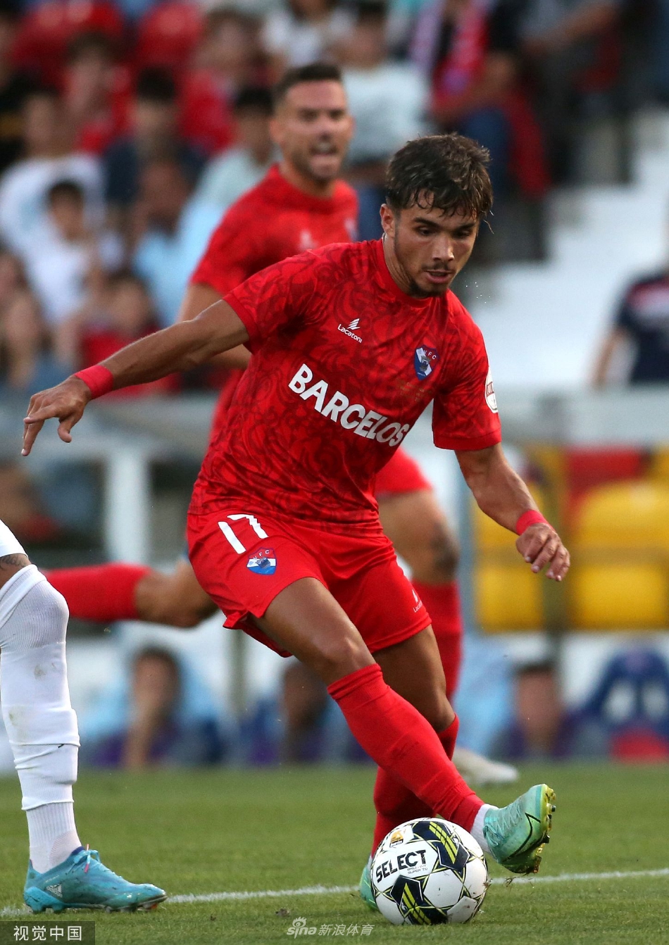 里加队门将飞身侧扑指尖险触皮球，身体在空中完全舒展，眼神紧盯着飞向死角的弧线球，无奈与坚韧交织在脸上。