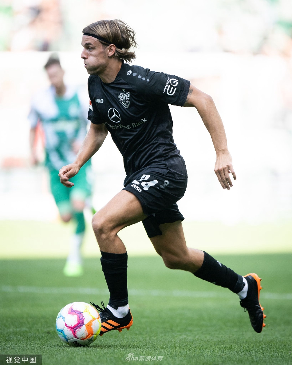 不莱梅球员进球后狂奔至角旗区，张开双臂激情庆祝，背景中队友正飞身扑来准备拥抱。