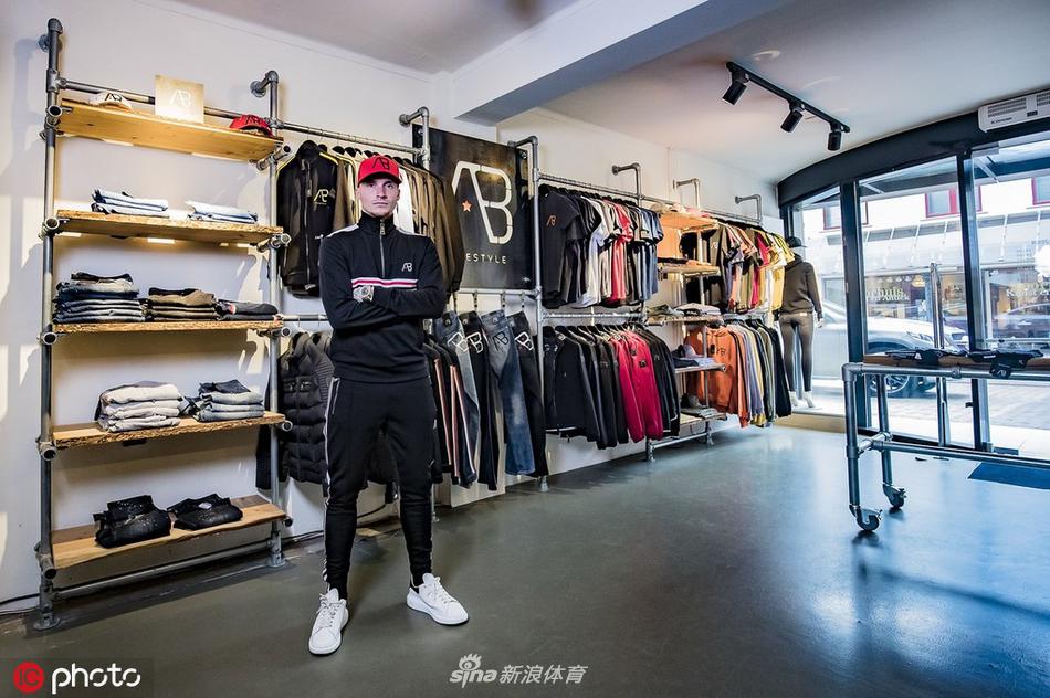 他倚靠砖墙，手臂自然交叉，凸显休闲服饰的舒适质感与荷兰小镇风情。