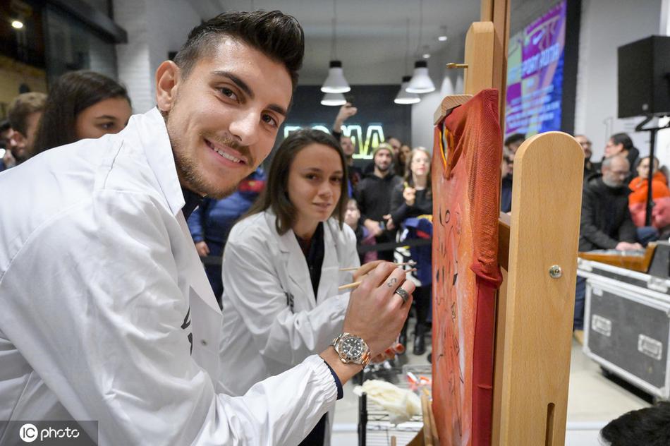 罗马球星云集活动现场，手握调色盘与画笔，眼神专注地审视空白画布，仿佛在构思一幅绝妙的进攻路线图，绿茵场外的艺术气息扑面而来。