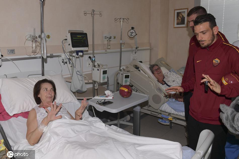 弗洛伦齐和桑顿在医院大厅与医护人员及患者家属合影，大家手中拿着签名球衣和纪念品，镜头定格在这一充满正能量的瞬间。