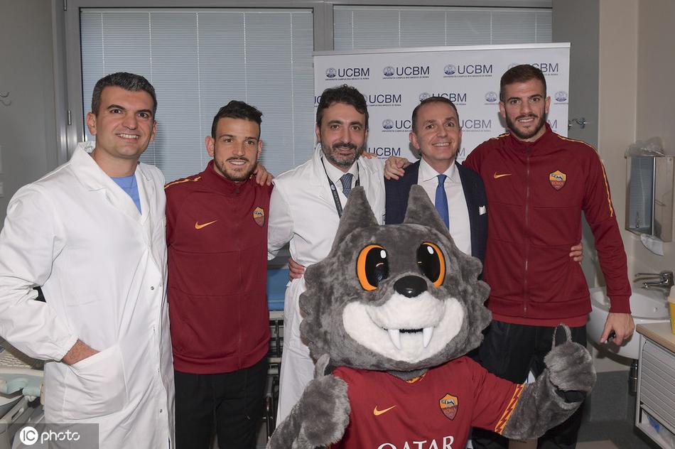 罗马后卫桑顿面带微笑，半蹲在病床前与一位小患者交谈，墙上色彩鲜艳的儿童画与这温馨一幕相映成趣，抚慰着幼小的心灵。