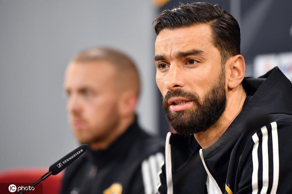 布拉加市政球场外景，傍晚时分灯光已然亮起，看台上的座椅在雨中泛着湿润的光泽，这座葡萄牙球场静待次日欧联杯小组赛狼队与布拉加的激烈对决。