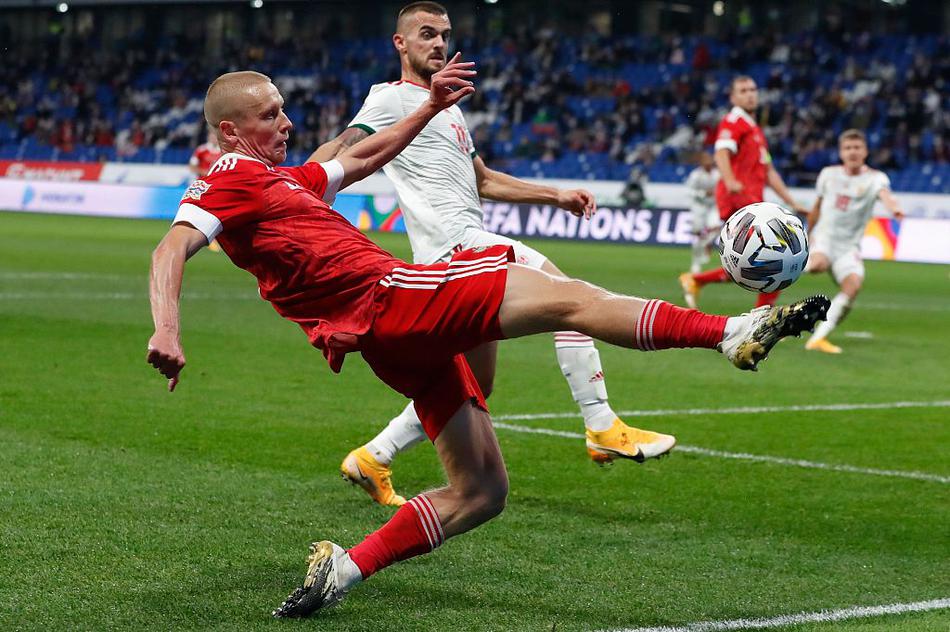 俄罗斯球员掩面蹲在草皮上，远处是匈牙利队员相互击掌庆祝，背景里看台上的灯光略显昏暗，衬托出一种壮志未酬的落寞。