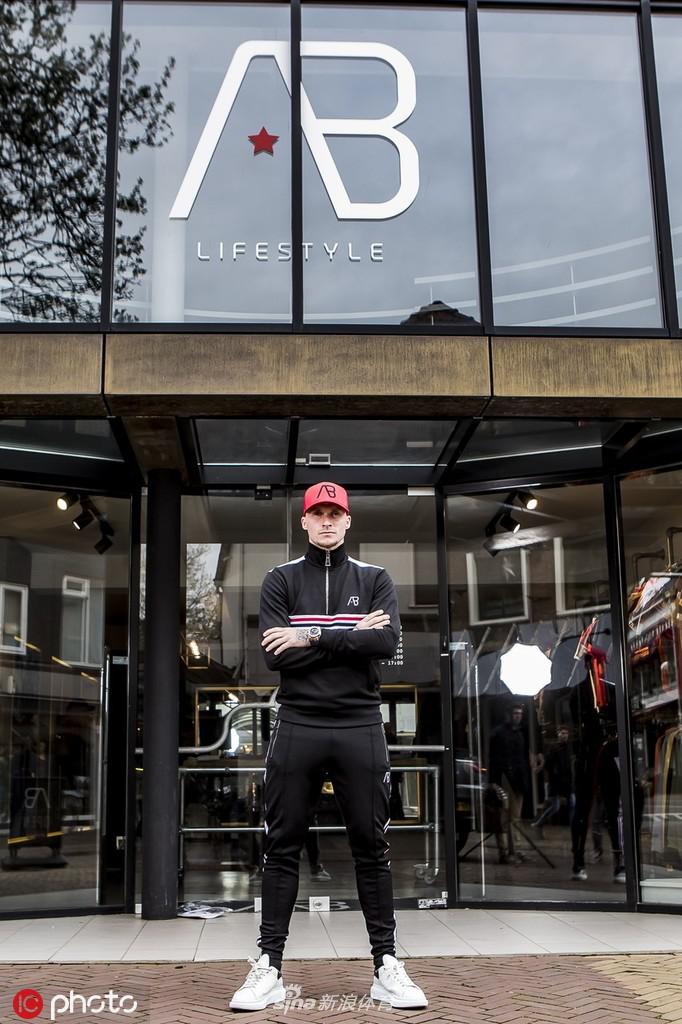 布特纳侧身望向远方，面带微笑，仿佛展望品牌未来，服装剪裁合体。