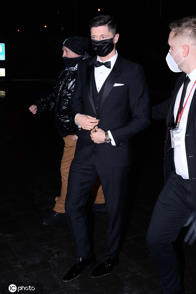 安娜独自站在镜头前，身后的光影虚化效果让她成为绝对焦点，她神态自若，手部的一个细微动作透露出优雅的防护意识，展现了成熟女性的魅力