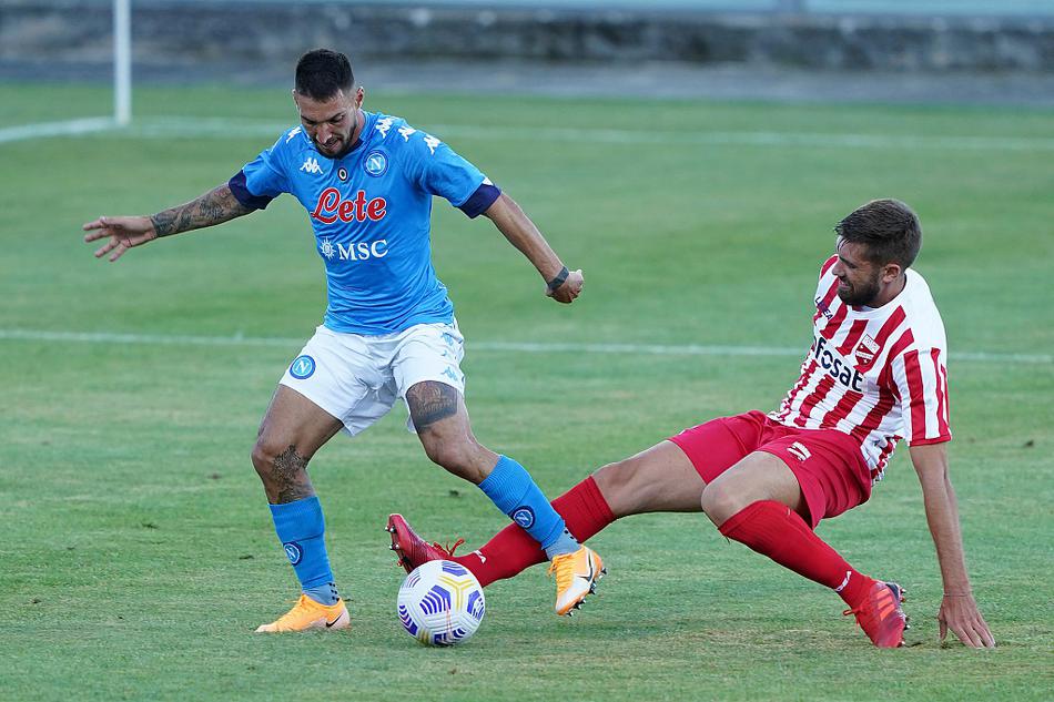 💪 比赛进行中，一名那不勒斯中场球员正在与特拉莫的防守队员进行激烈的一对一缠斗。他压低重心，用身体卡住身位，同时伸出右脚努力将球控制在脚下，双方手臂纠缠在一起，肌肉线条分明，充满了力量感。