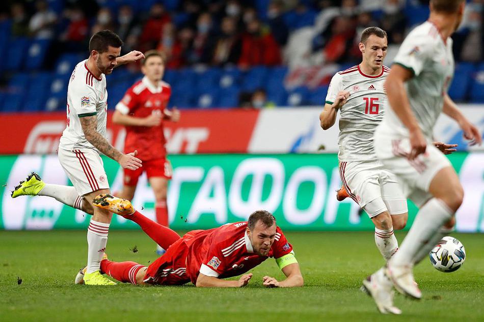 匈牙利防守球员飞身铲截，皮球在草皮上溅起细碎的水花，他的眼神紧盯着滚动的足球，身后是俄罗斯进攻球员懊恼的身影。