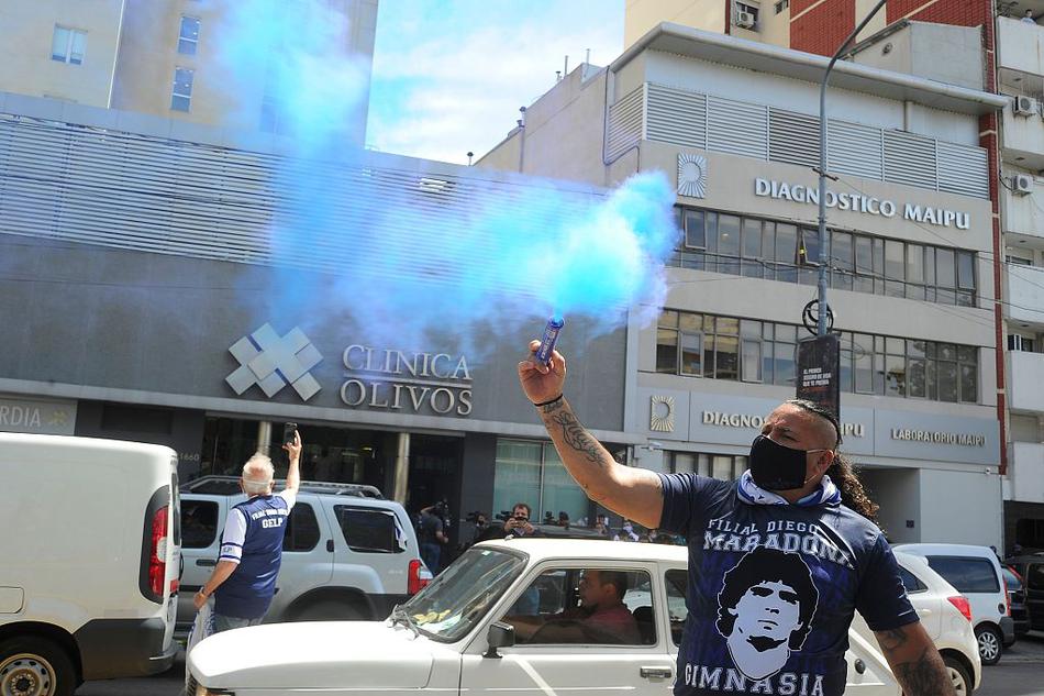 在拉普拉塔的医院外，数名身披阿根廷国旗的忠实球迷久久不愿离去，他们眼神专注地望向医院大楼，无声地传递着对球王的虔诚祝福