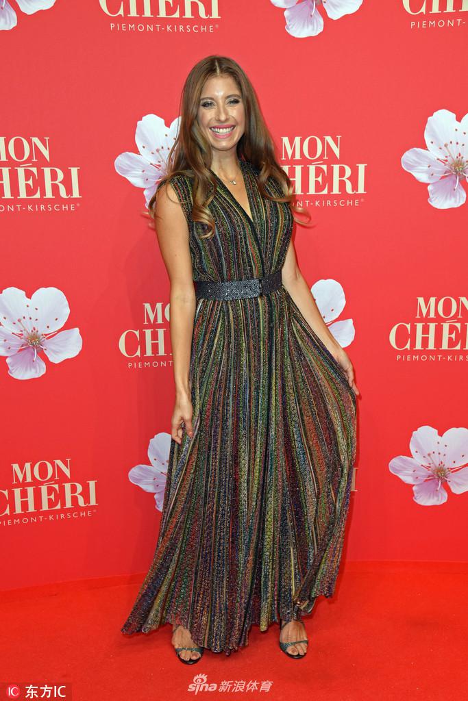 凯茜身着一袭剪裁得体的素雅长裙，在室内灯光下浅笑盈盈，优雅气质宛如冬日里的一抹暖阳