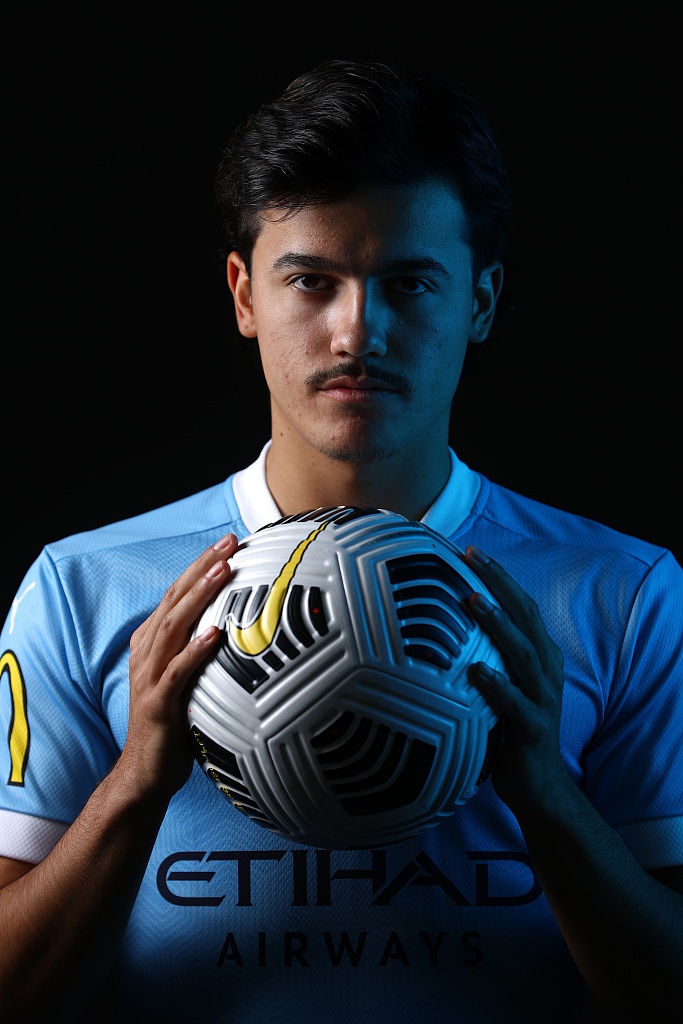 一名墨尔本城球员整理着袖标，低头沉思的瞬间被捕捉，背景虚化的球场看台仿佛诉说着过往的喧嚣，而他的专注只为了在即将到来的战役中倾尽所有。