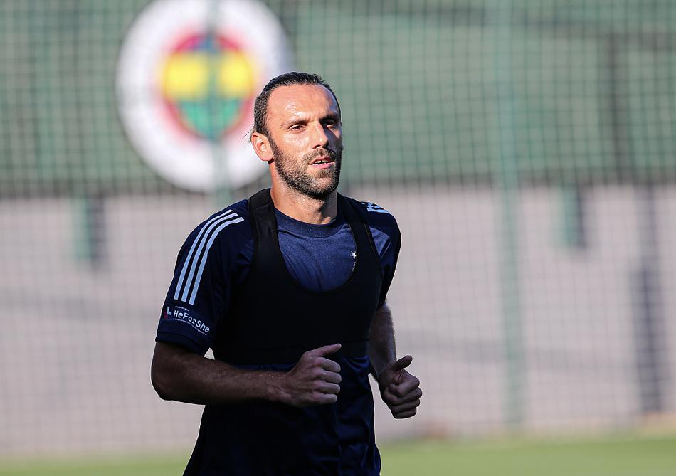 费内巴切球员们身着深色训练服，在午后阳光下全神贯注地进行分组对抗，摄影师以低角度捕捉到了球员带球突破瞬间草皮飞溅的动感画面。