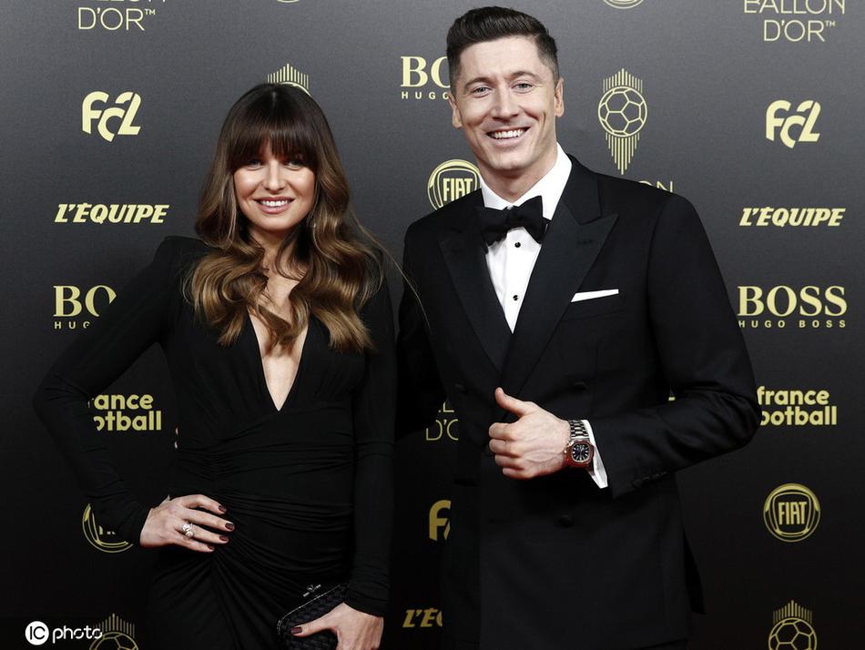 莱万多夫斯基夫妇在休息区亲切交谈，安娜笑得开怀，莱万则温柔地注视着她，两人之间默契与甜蜜的氛围溢于言表。