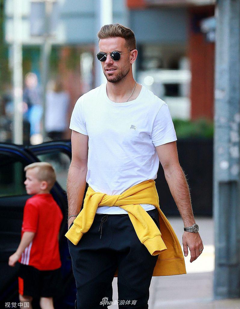 亨德森面带微笑，眼神坚定，他身披利物浦队旗，在街头与簇拥的球迷们互动，享受着冠军带来的无上荣光。