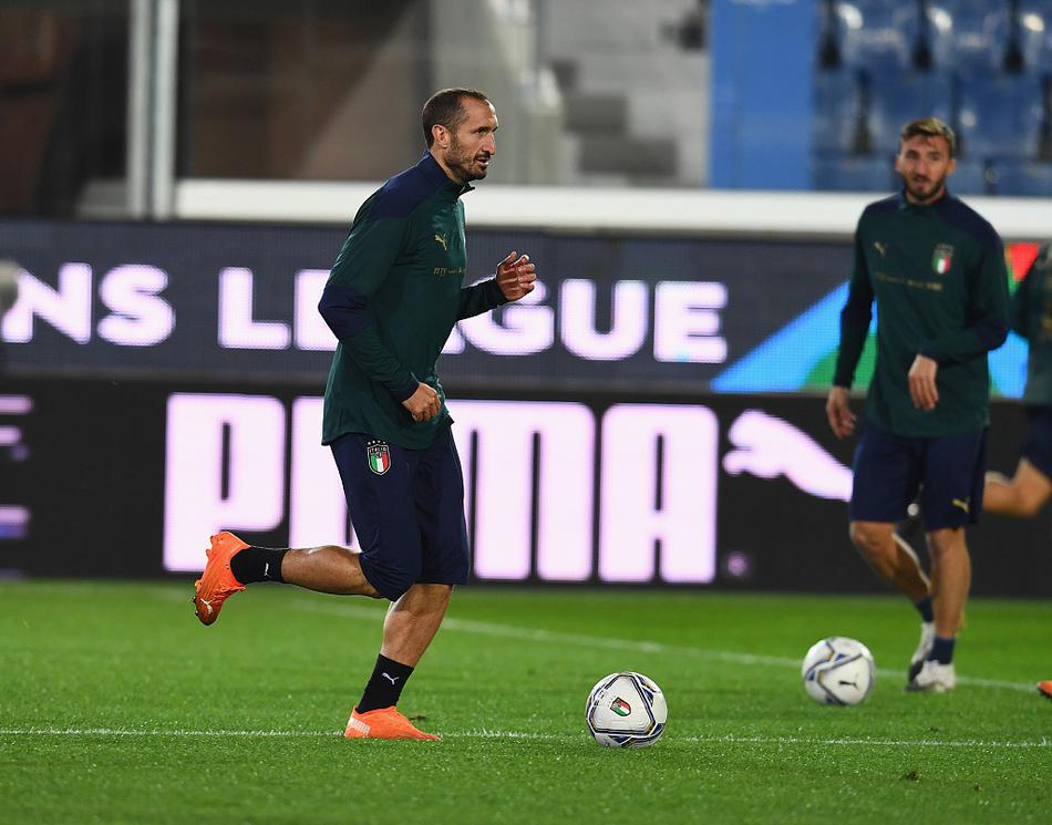 队长基耶利尼在训练中大声指挥着队友，他的眼神坚毅，手臂用力指向远方，仿佛要用经验为这支年轻的队伍筑起一道无形的防线。