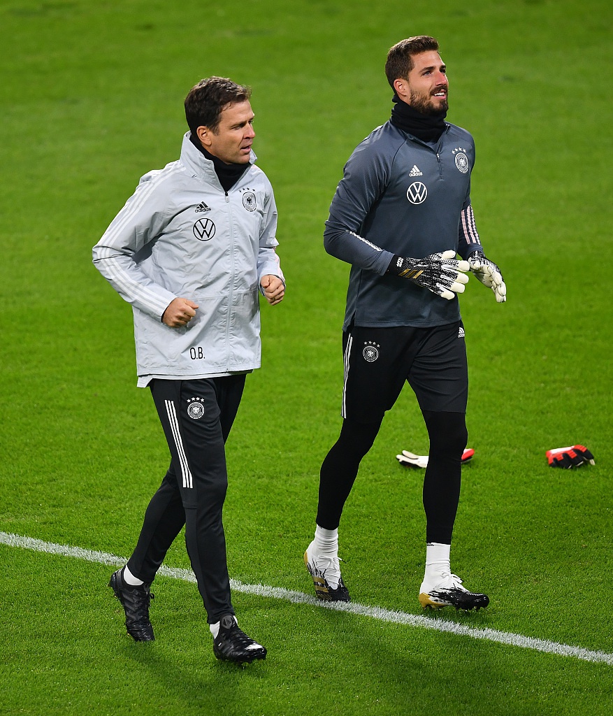 一名球员正在调整自己的护腿板，他低着头，神情一丝不苟。这个看似微不足道的细节，却被镜头放大。护腿板上沾着草屑和泥土，那是属于战士的勋章，也昭示着他对即将到来的战斗做好了万全的准备。