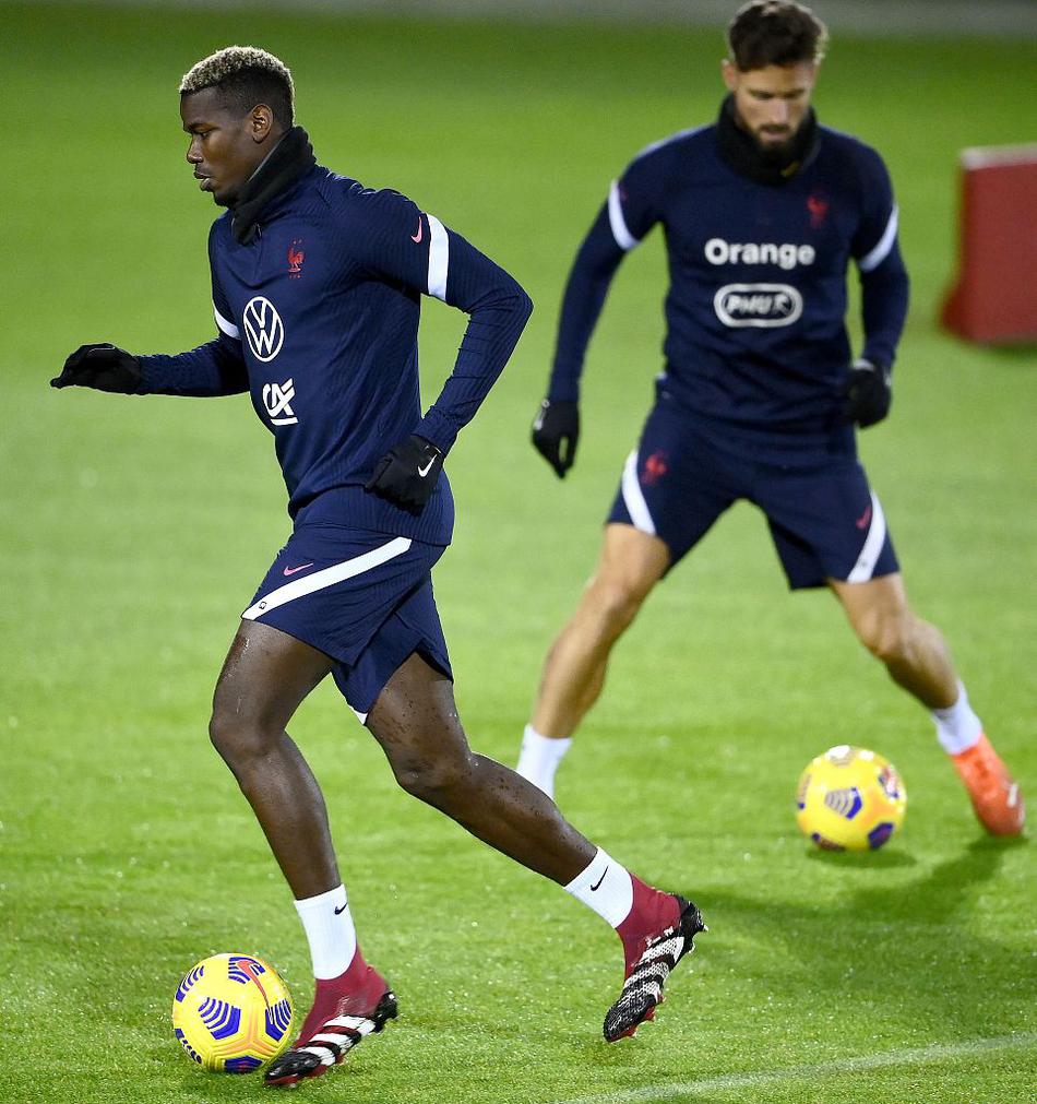 主教练德尚在场边亲自上阵指导，他双手插兜，身体前倾，专注地为球员讲解战术跑动路线，展现了名帅的严谨与细致。