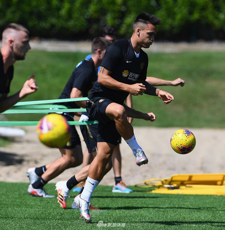 一名球员正在进行身体拉伸，阳光勾勒出他健硕的背部线条，远处的队友们也在进行着各自的准备活动，这张照片宁静中透着力量，展现了职业球员对身体管理的一丝不苟。