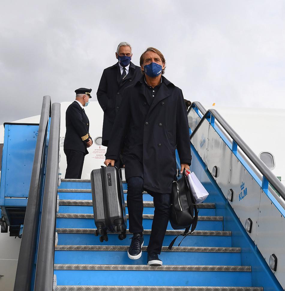 在酒店门口，因莫比莱低头拉着行李箱，面带微笑地与等候的意大利球迷打招呼，行李箱上挂着的幸运符在异国阳光下格外醒目。