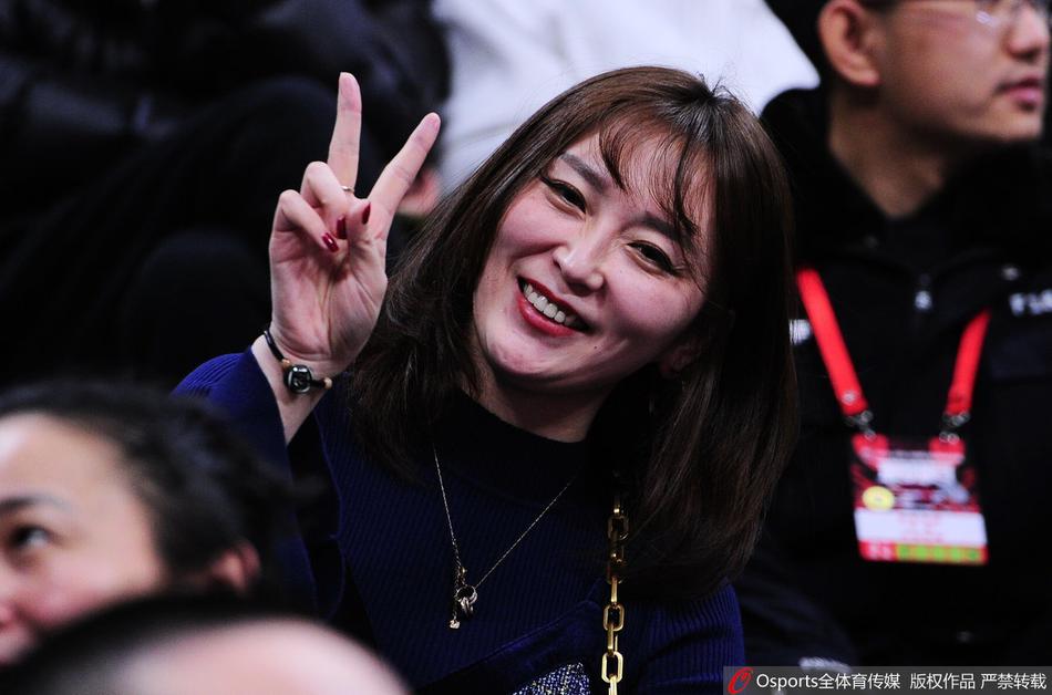 美女球迷面带微笑，眼神中闪烁着对主队胜利的渴望，她用手轻轻托着下巴，仿佛在思考场上瞬息万变的战术，又像在默默为心中的英雄祈祷。