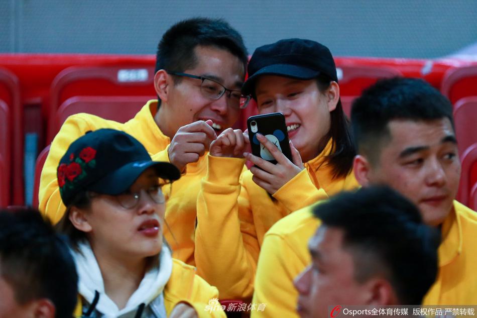 一位长发披肩的女生，在人群中回眸一笑，眼神清澈而专注，她手中似乎拿着什么，但更吸引人的是她那份在喧闹赛场中依然保持的优雅与从容，宛如球场边的一缕清风。