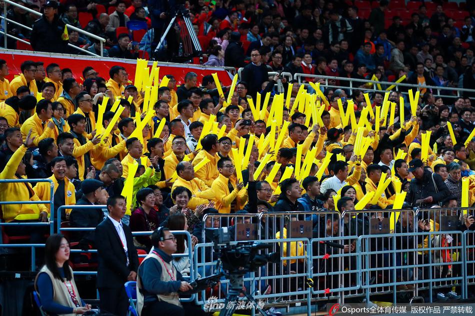 这位身穿橙色志愿者马甲的女孩，在被镜头捕捉到的瞬间，露出了略带羞涩又无比灿烂的笑容，身后的喧嚣仿佛都被虚化，只留下她这一抹温暖了整个球馆的明媚。