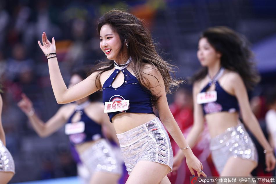 镜头捕捉到一位啦啦队领舞的灿烂笑容，她身姿挺拔，动作舒展，手中的花球随着强劲的音乐节拍上下翻飞，仿佛在诉说着篮球场上力与美的完美融合。