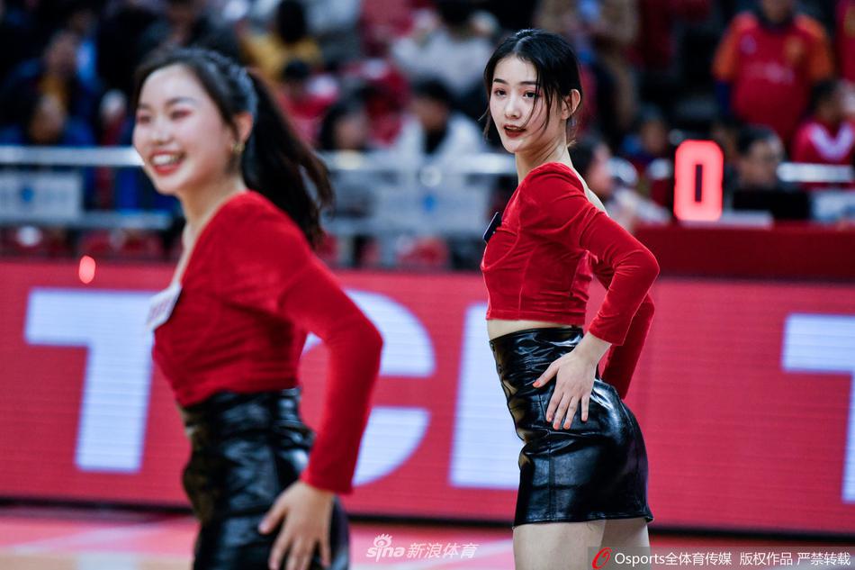 镜头拉近，这位领舞的篮球宝贝眼神专注而有力，手中的花球随着精准的舞步上下翻飞，每一个动作都充满了青春的力量和韵律感，背景是模糊的看台人海。