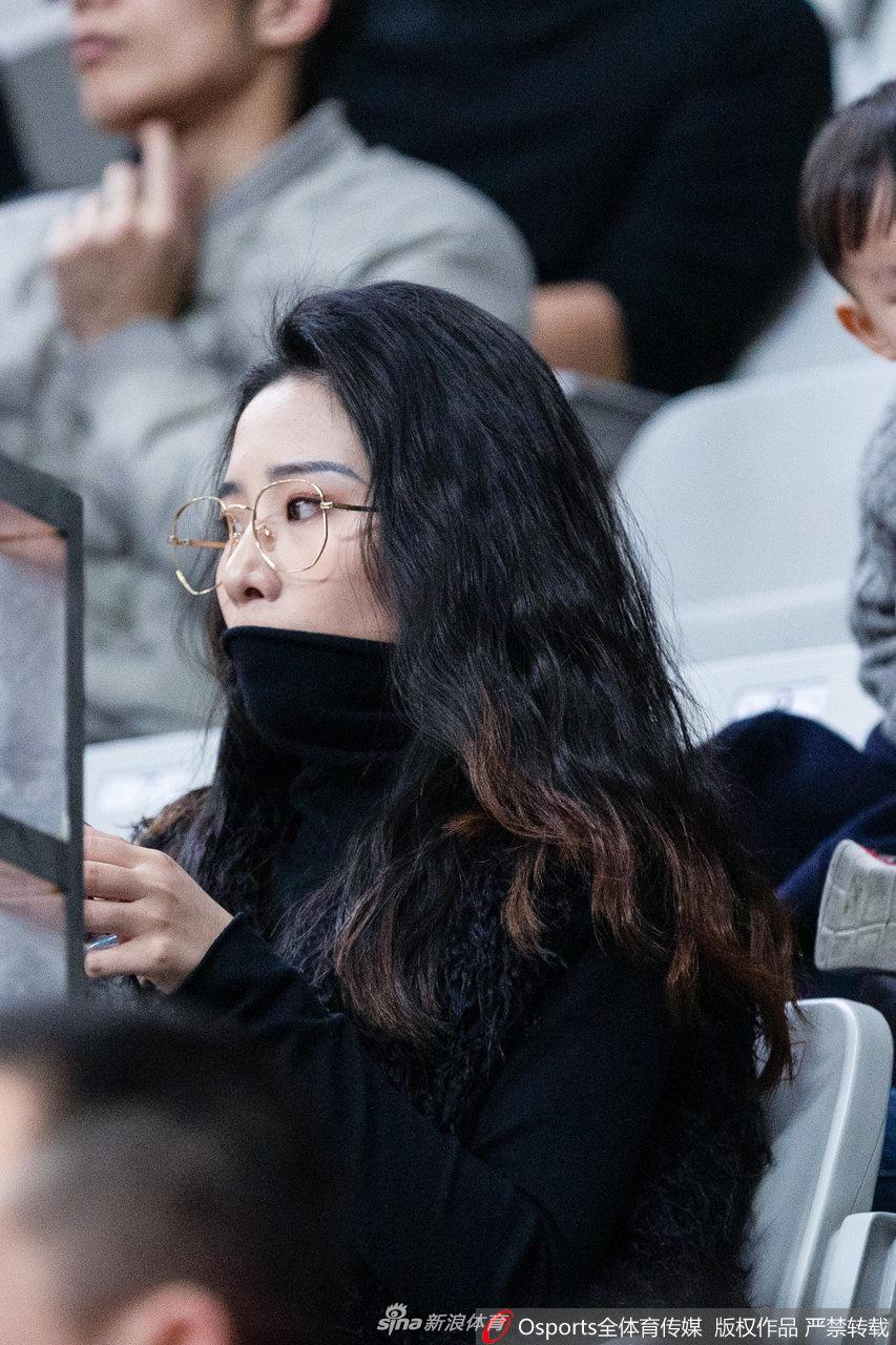 一位扎着清爽丸子头的浙江美女球迷，身穿休闲卫衣，正举起手机记录下赛场上的精彩瞬间，她身后的球迷们或振臂高呼，或全神贯注，共同构成了鲜活的现场图景。