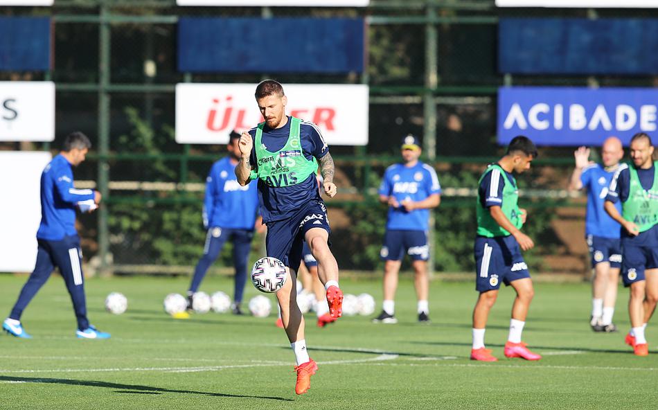 几名费内巴切防守球员正在进行高强度的压迫练习，队长袖标的球员正挥手指挥队友站位，背景中可以看到教练组成员在战术板前观察。