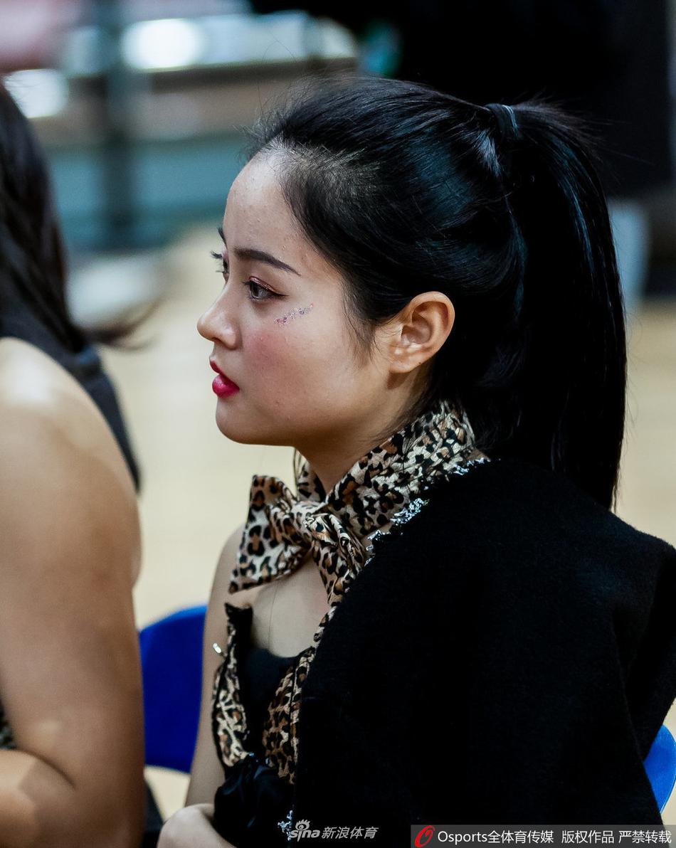 一位篮球宝贝背对镜头，单手高高指向天空，马尾辫随着动作甩出优美的弧线。紧身舞裙勾勒出动感的身姿，即使只是背影，也能感受到那份专注与投入。