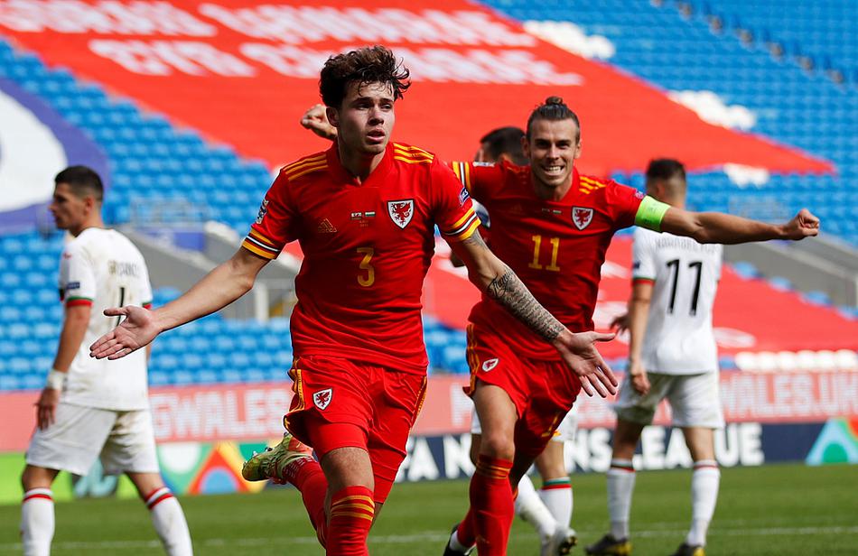 威尔士中场悍将奋力跃起，在与保加利亚防守球员的激烈对抗中争顶头球，他肌肉紧绷，眼神坚毅，定格了中场争夺战的火药味与紧张感。